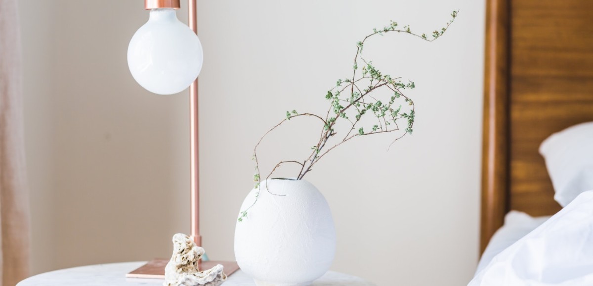 Modern table lamp with planter on nightstand next to bed