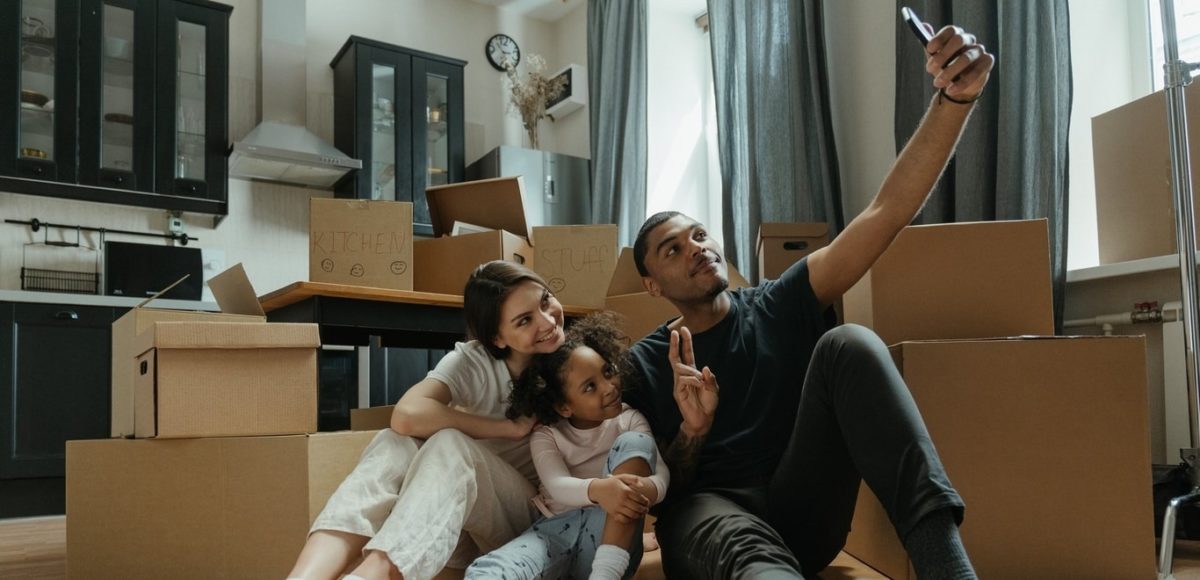 family taking a selfie in front of moving boxes