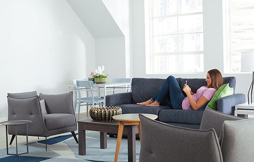 Woman on phone sitting on sofa in contemporary style living room.