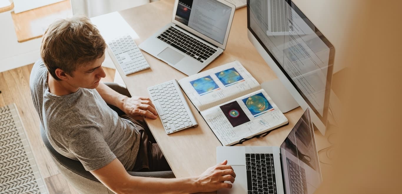 Man working at desk with multiple laptops and screens