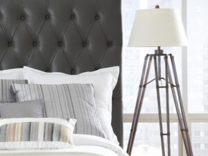 Industrial lamp next to bed with neutral toned covering 