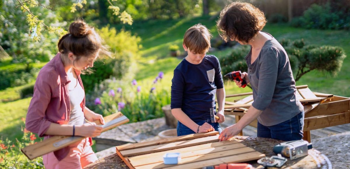 Woman outside working on a DIY project with her son and daughter