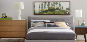 Modern bedroom with neutral colors, decorative throw pillows, and nature-inspired artwork