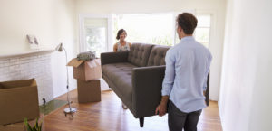 Couple carrying sofa into home afer moving into first place starting life after college they chose the best furniture for a first house.