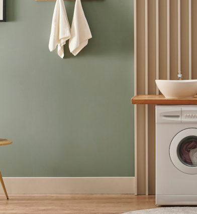 Washing machine in fashionable laundry room with green walls, warm woods, DIY countertop, and accent wall