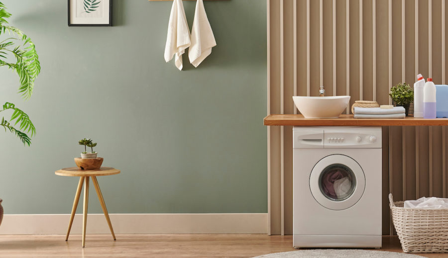 Washing machine in fashionable laundry room with green walls, warm woods, DIY countertop, and accent wall