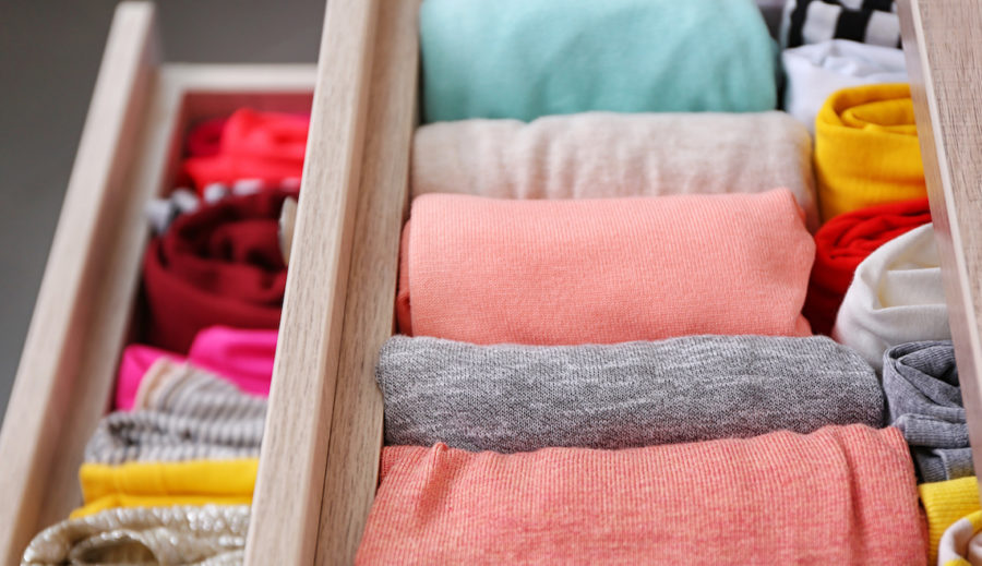 Neatly folded clothes in chest of drawers in bedroom storage furniture.
