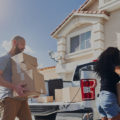 Couple moving locally loading boxes into car as a way to save money when moving locally outside of a house.