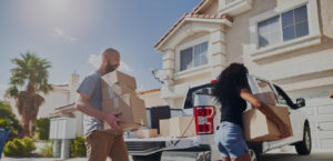 Couple moving locally loading boxes into car as a way to save money when moving locally outside of a house.
