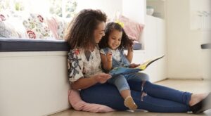 Mom and young daughter reading a book together