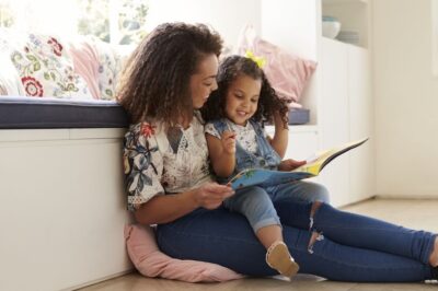 Mom and young daughter reading a book together