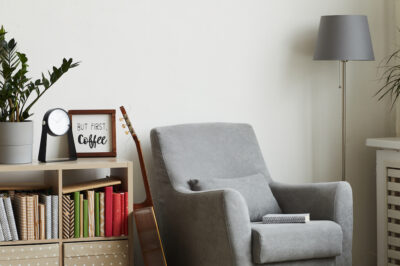 Background image of cozy reading nook in modern minimal interior, focus on grey armchair against white wall, formerly unused spaces in your home like a repurposed or unused dining room