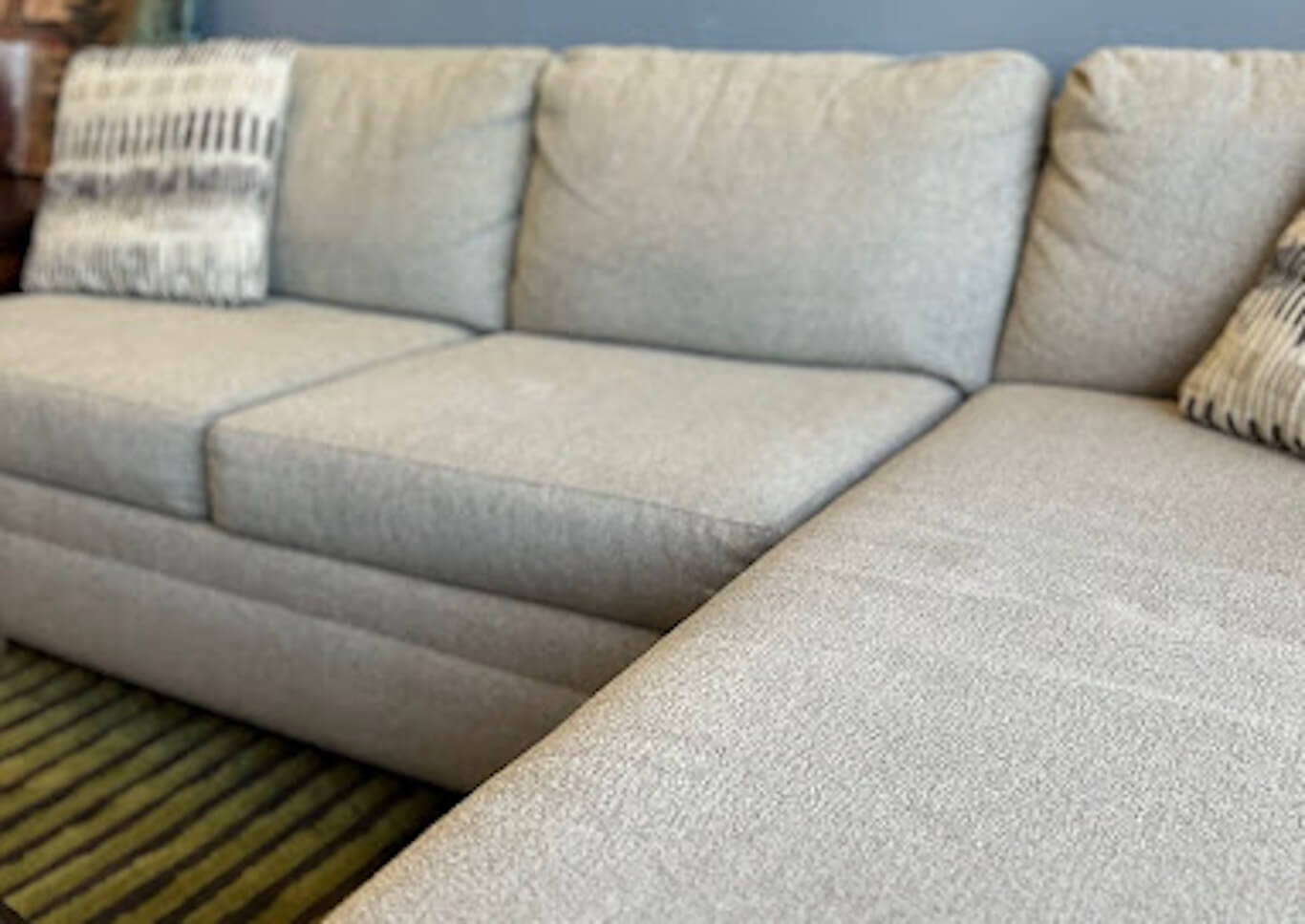 A grey sectional sofa with decorative pillows in a furniture showroom.