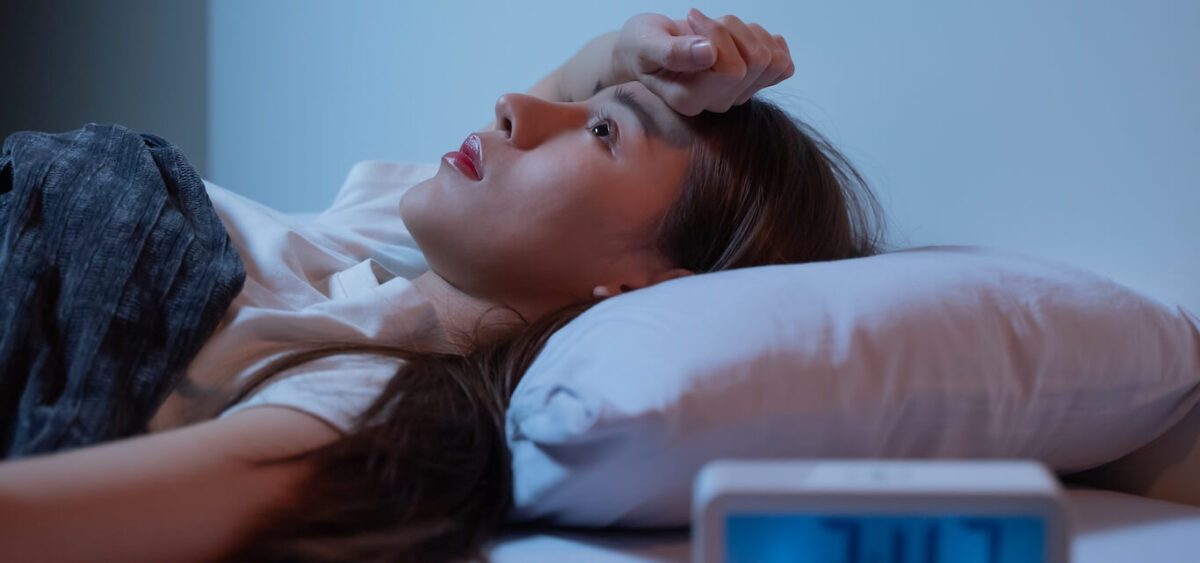 Woman laying in bed, staring at the ceiling unable to sleep.