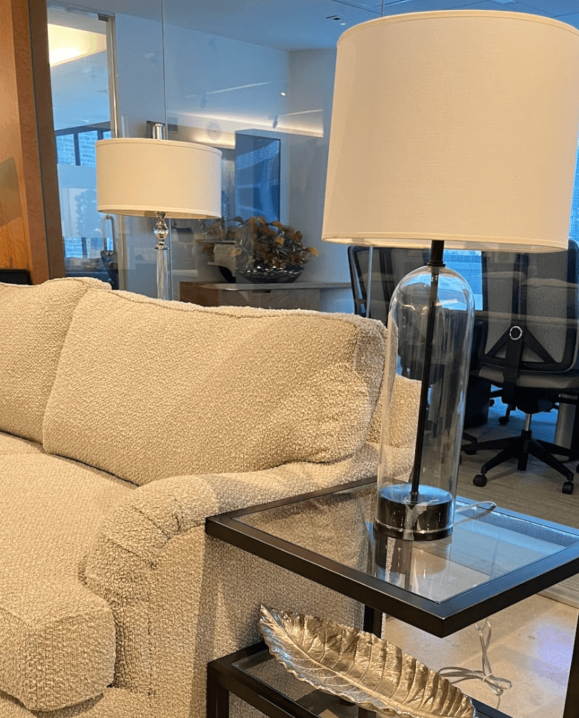 Lamp with a clear base sitting on a glass table.