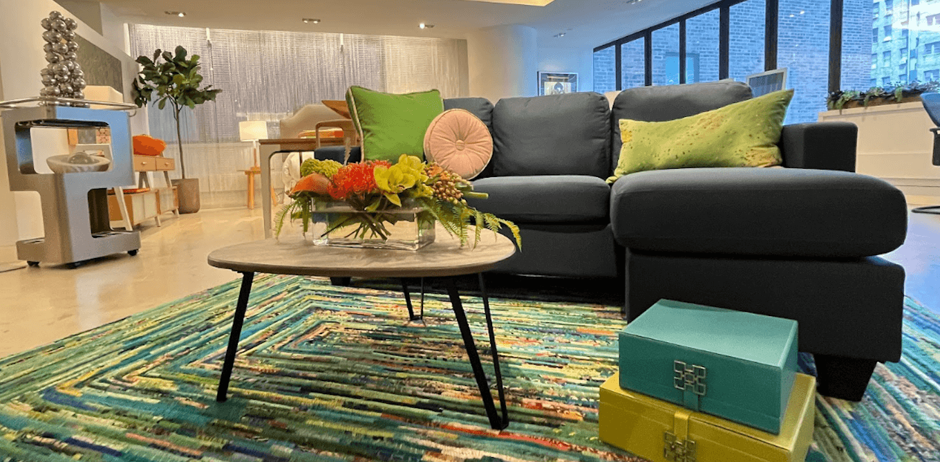 A colorful rug, bright throw pillows, and dark sofa.