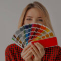 A woman holding a rainbow of paint swatches.