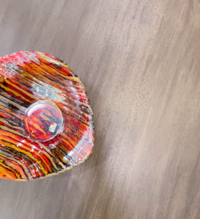 A dark red, orange, and yellow piece of glass artwork on a table.