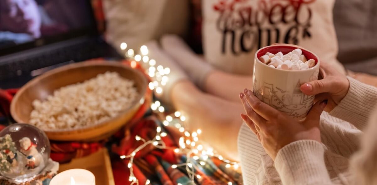 A person enjoying a hot chocolate surrounded by holiday decorations.