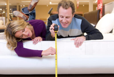A couple measuring the size of their mattress.