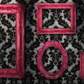Black and white vintage wallpaper with bright pink picture frames.