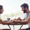 Woman and man sitting at small dining table bistro table outside after finding a stylish inexpensive small dining table for sale.