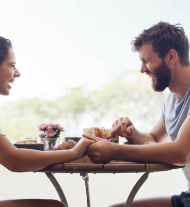 Woman and man sitting at small dining table bistro table outside after finding a stylish inexpensive small dining table for sale.