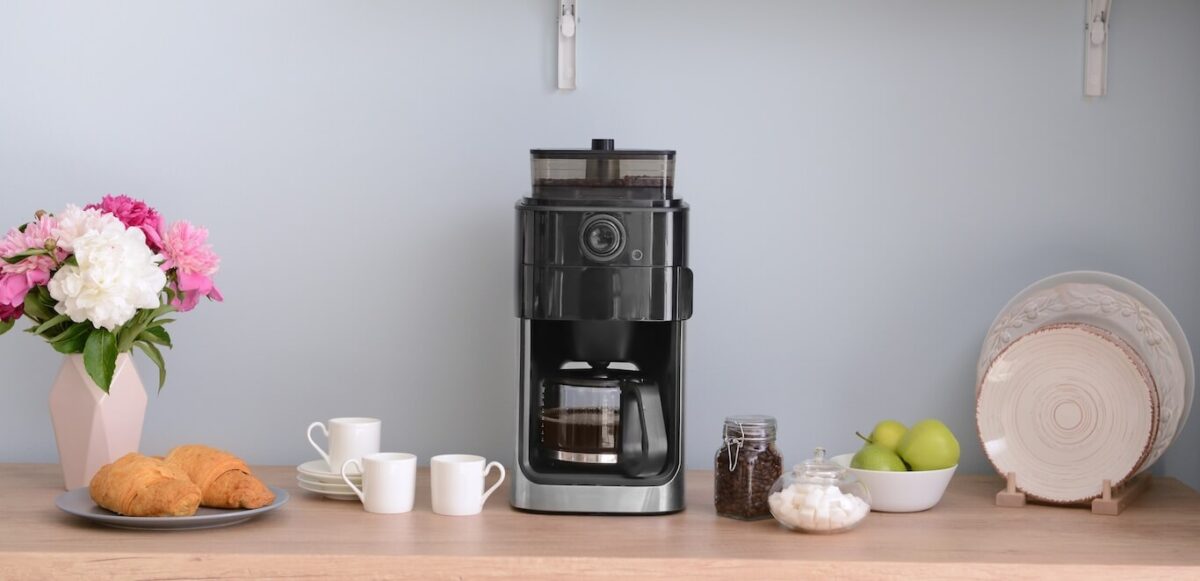 A home coffee bar with a coffee maker, coffee cups, and pastries on plates.