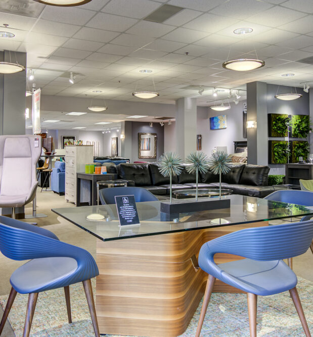A well-lit furniture showroom featuring a mix of dining tables, chairs, lounge seating, and wall decor, highlighting CORT Furniture Outlet’s variety of stylish furniture.