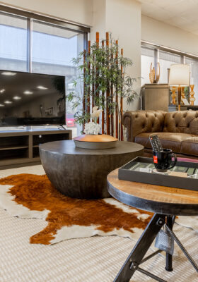 A modern living room setup with a brown leather sofa, accent chairs, a large TV stand, and decorative elements, showcasing CORT Furniture Outlet’s high-quality furniture.