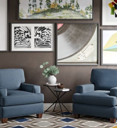Stylish eco friendly furniture and sustainable furniture near you at CORT Furniture outlet, including new and gently used furniture demonstrated in a living room styled with two blue armchairs, a gallery wall, and patterned rug underfoot