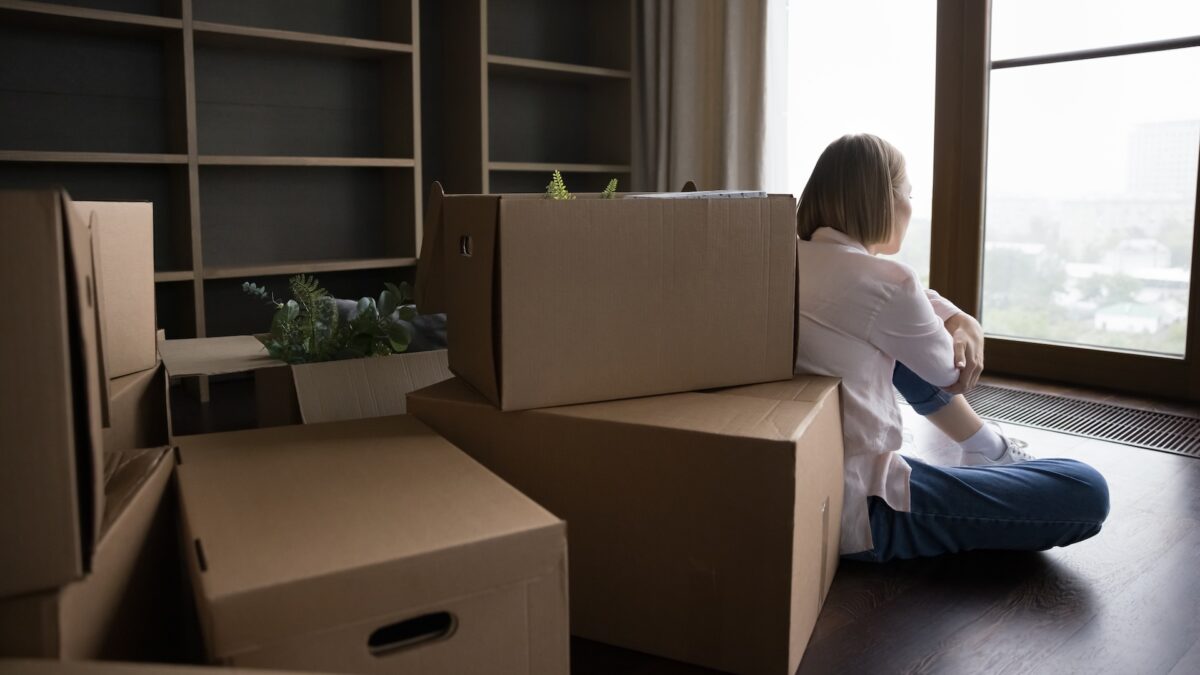 Woman experiencing homebuyers remorse after moving into new house sitting amidst moving boxes wondering if you can sell a house you just bought