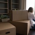 Woman experiencing homebuyers remorse after moving into new house sitting amidst moving boxes wondering if you can sell a house you just bought