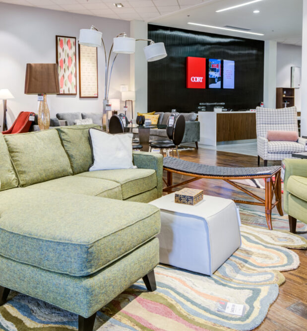 A stylish green sectional and accent chairs at CORT Furniture Outlet, showing how the end of fast furniture makes room for affordable, sustainable pieces that still feel high-end.